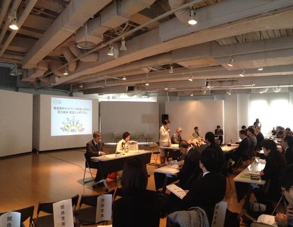 「創造都市ネットワーク日本」設立総会・記念シンポジウム会場で白いスーツを着た女性が右手にマイクを持ち話しをしている写真